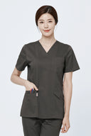 Model wearing Burnt Brown Avison Scrub Top in a clinical setting, three-quarter view