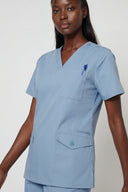 Model wearing Soft Blue Avison Scrub Top in a studio setting, three-quarter view