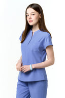 Model wearing Lavender Blue CST202 Scrub Top in a studio setting, three-quarter view