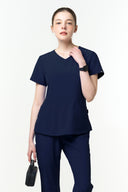 Model wearing Warm Navy CST203 Scrub Top in a studio setting, three-quarter view