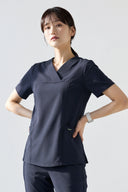 Model wearing Navy ST215 Scrub Top in a studio setting, three-quarter view
