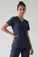 Model wearing Dark Navy Anyone Zip Scrub Top in a clinical setting, three-quarter view