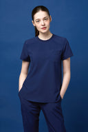 Model wearing Warm Navy CST201 Scrub Top in a studio setting, three-quarter view