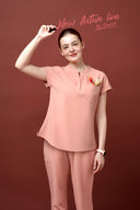 Model wearing Coral Peach CST202 Scrub Top in a studio setting, three-quarter view