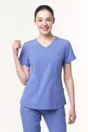 Model wearing Lavender Blue CST203 Scrub Top in a studio setting, three-quarter view