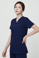 Model wearing Modern Navy Avison Scrub Top in a studio setting, three-quarter view