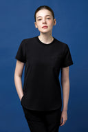 Model wearing Grey CST201 Scrub Top in a blue studio background, three-quarter view