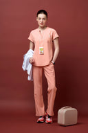 Model wearing Coral Peach CST202 Scrub Top by Good Uniform, full front view