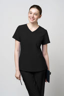 Model wearing Jet Black CST203 Scrub Top in a clinical setting, three-quarter view
