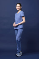 Model wearing Lavender Blue CST203 Scrub Top by Good Uniform, full front view slightly from the side