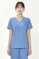 Model wearing Reef Blue ST002 Scrub Top in a studio setting, three-quarter view