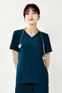 Model wearing Turkey Green ST002 Scrub Top in a studio setting, three-quarter view