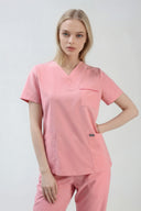 Model wearing Indi Pink ST247 Scrub Top in a studio setting, three-quarter view