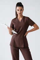 Model wearing Brown Anyone Zip Scrub Top in a clinical setting, three-quarter view