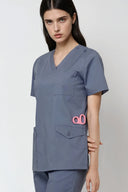 Model wearing Mist Grey Avison Scrub Top in a studio setting, three-quarter view