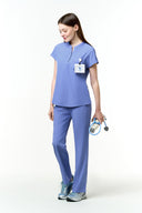 Model wearing Lavender Blue CST202 Scrub Top by Good Uniform, full front view