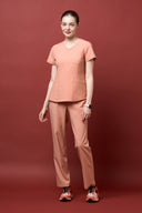 Model wearing Coral Peach CST203 Scrub Top by Good Uniform, full front view