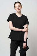 Model wearing Jet Black CST203 Scrub Top in a studio setting, three-quarter view form the front holding a note