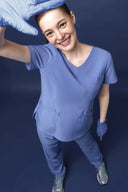 Model wearing Lavender Blue CST203 Scrub Top by Good Uniform, shot from top looking down at the model