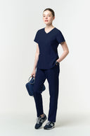 Model wearing Warm Navy CST203 Scrub Top by Good Uniform, full front view
