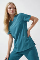 Model wearing Aquamarine ST215 Scrub Top in a studio setting, three-quarter view