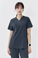 Model wearing Cool Grey ST215 Scrub Top in a studio setting, three-quarter view from front
