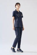 Model wearing Navy ST215 Scrub Top by Good Uniform, full front view
