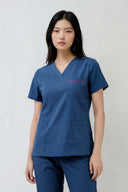 Model wearing Methyl Blue ST247 Scrub Top in a studio setting, three-quarter view
