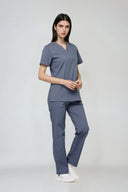 Model wearing Mist Grey Avison Scrub Top by Good Uniform, full front view slightly from the side