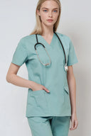 Model wearing Vintage Mint Avison Scrub Top with a hand in the pocket in a studio setting, three-quarter view