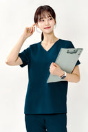 Model wearing Turkey Green ST002 Scrub Top in a clinical setting, three-quarter view