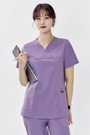 Model wearing Lavandula ST215 Scrub Top in a clinical setting, three-quarter view