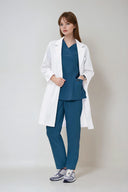 Model wearing Methyl Blue ST215 Scrub Top and lab coat by Good Uniform, full front view
