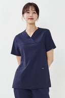 Model wearing Royal Purple ST215 Scrub Top in a studio setting, three-quarter view