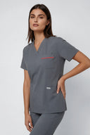 Model wearing Smoky Grey ST247 Scrub Top in a studio setting, three-quarter view slightly from the side