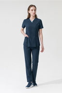 Model wearing Antique Blue Anyone Zip Scrub Top by Good Uniform, full front view