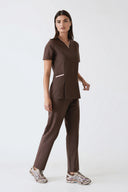 Model wearing Brown Anyone Zip Scrub Top by Good Uniform, full front view slightly from the side
