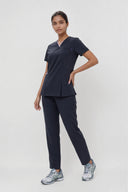 Model wearing Dark Navy Anyone Zip Scrub Top by Good Uniform, full front view slightly from the side