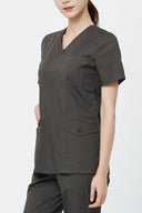 Pocket, neckline and seam details on the Burnt Brown Avison Scrub Top from the side