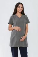 Model wearing Mild Grey NF30 Maternity Scrub Top in a studio setting, three-quarter view