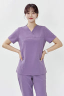 Model wearing Lavandula ST215 Scrub Top in a studio setting, three-quarter view