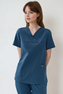 Model wearing Methyl Blue ST215 Scrub Top in a studio setting, three-quarter view