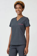 Model wearing Deep Slate ST247 Scrub Top in a clinical setting, three-quarter view slightly from side