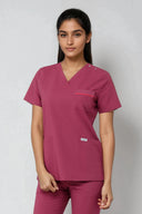 Model wearing Dusty Rose ST247 Scrub Top in a studio setting, three-quarter view
