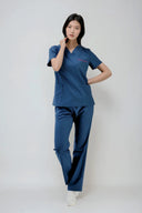 Model wearing Methyl Blue ST247 Scrub Top by Good Uniform, full front view