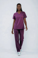 Model wearing Plum Purple ST247 Scrub Top by Good Uniform, full front view