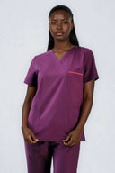 Model wearing Plum Purple ST247 Scrub Top in a studio setting, three-quarter view from the front