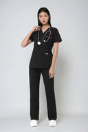 Model wearing Black ST247 Scrub Top by Good Uniform, full front view